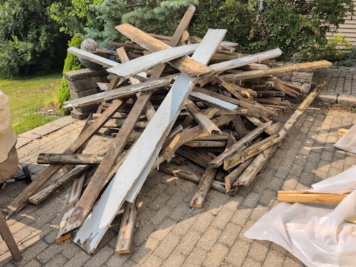 Demolished deck boards piled on a patio before removal